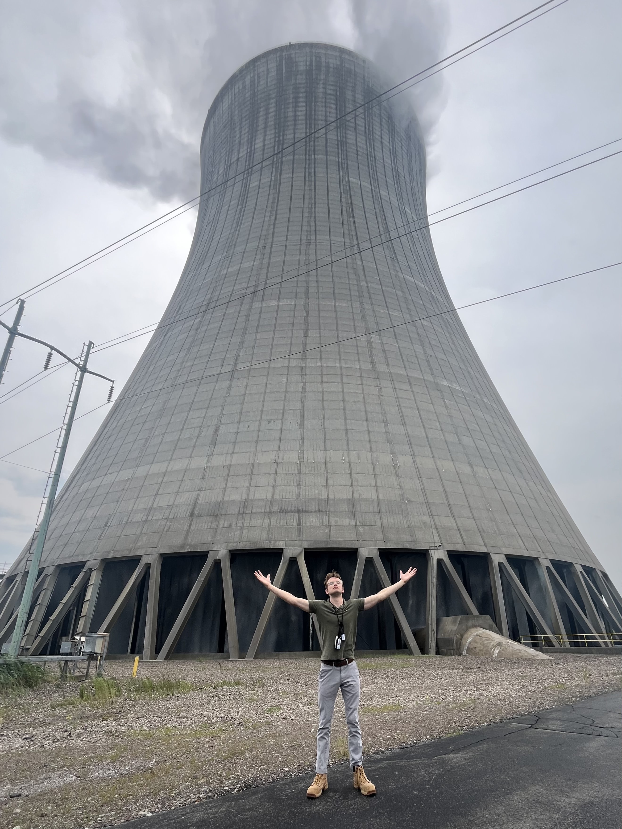 Adam Heiler standing in front of a cooling tower at Nine Mile Point Clean Energy Center